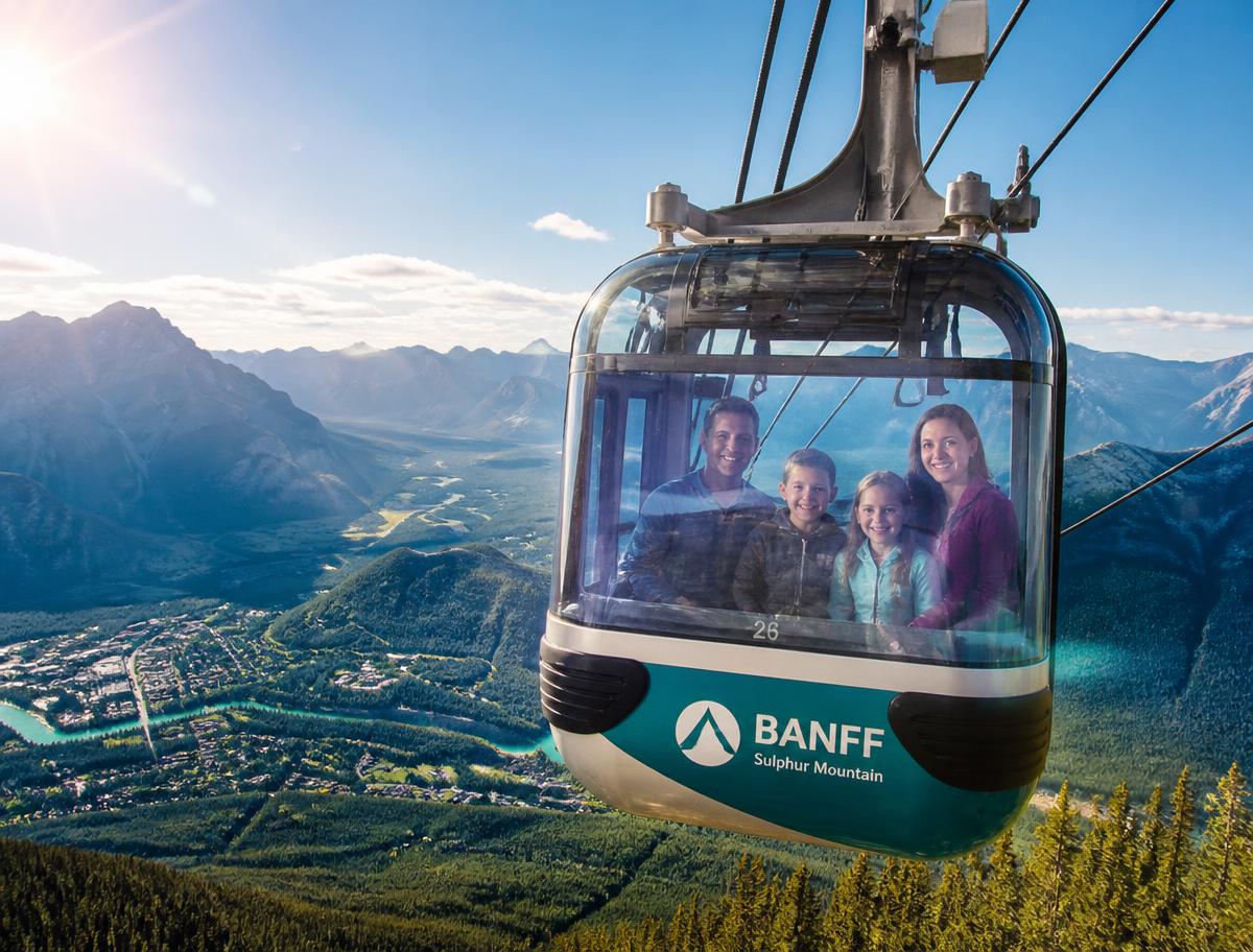 A smiling family riding the Banff gondola above the Bow Valley in bright sunshine